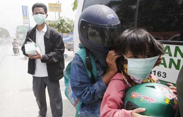 Habitantes se protegen de cenizas de volcán.