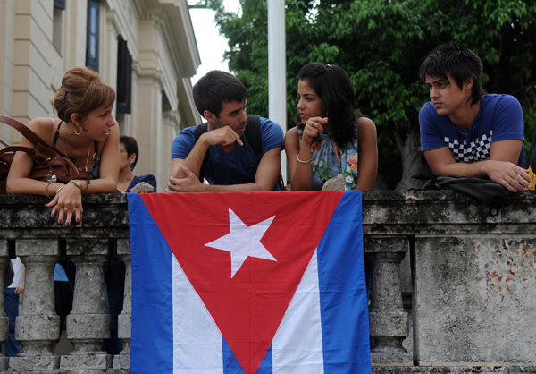 Jóvenes cubanos junto a la enseña nacional 