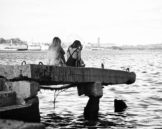 Muchachas al atardecer contemplando el paisaje y tomando el  fresco en la Bahía de la Habana