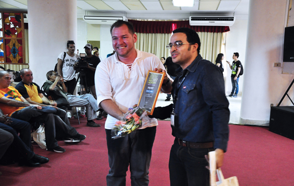Rubiel García, presidente de la AHS (derecha), entregó a Maikel Rodríguez el reconocimiento que lo acredita como el ganador en literatura infantil por La isla iluminada