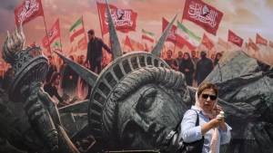 Una iraní pasa junto a cartel contra la agresión estadounidense en Teherán.
