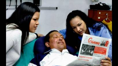 Chávez lee el diario Granma junto a sus hijas