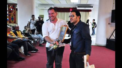 Rubiel García, presidente de la AHS (derecha), entregó a Maikel Rodríguez el reconocimiento que lo acredita como el ganador en literatura infantil por La isla iluminada