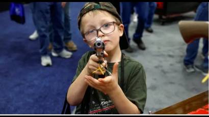 Su propio padre puso la pistola en sus manos de seis años en la convención de la Asociación Nacional del Rifle. 