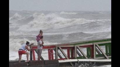 Una familia observa las altas olas del huracán Hanna desde un muelle en Galveston, Texas.