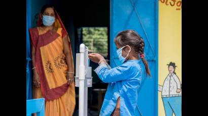 Estudiante de seis años en India usa desinfectante de pedal para practicar la higienización de las manos.
