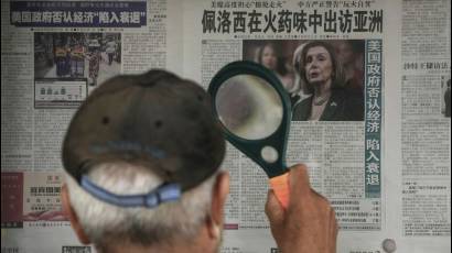 Un hombre utiliza una lupa para leer en un periódico de Beijing información sobre posible visita de Nancy Pelosi a Taiwán.