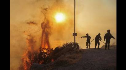 Bomberos intentan extinguir un incendio forestal que arde en Saronida, cerca de Atenas, Grecia