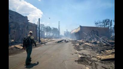 Hombre pasa junto a restos de un incendio forestal en Lahaina