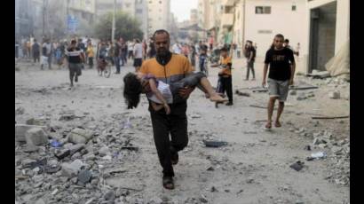 Palestino carga a un infante herido luego de un bombardeo israelí
