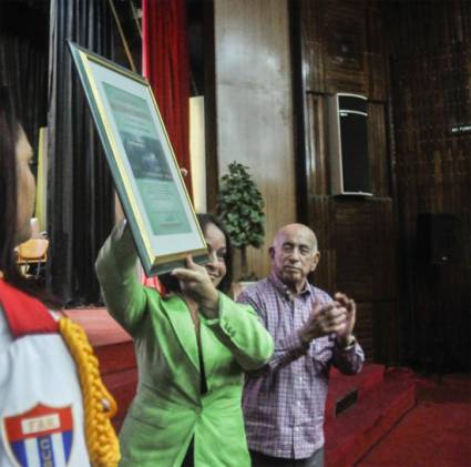 La MSc. Rosario Pentón Díaz, rectora de la Escuela Nacional del Partido Ñico López, recibe el reconocimiento por el aniversario 55 del Sistema de Escuelas del Partido, de manos de José Ramón Machado Ventura.