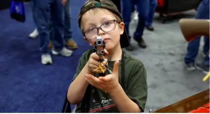 Su propio padre puso la pistola en sus manos de seis años en la convención de la Asociación Nacional del Rifle. 
