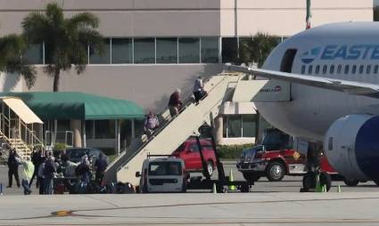 Trabajadores medicos guian a un paciente del crucero Zaandam hacia una ambulancia que espera en Fort Lauderdale