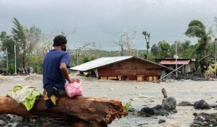 Un hombre observa su casa sepultada por escombros y arena tras las inundaciones repentinas provocadas por el tifón Goni