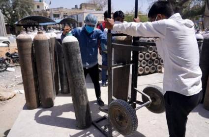 Unos trabajadores colocan bombonas de oxígeno usadas para pacientes con coronavirus en unas instalaciones del hospital Jawaharlal Nehru de la ciudad de Ajmer, al noroeste de India