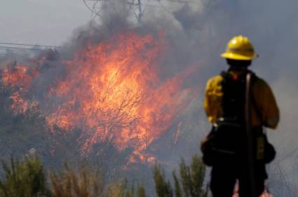 Un bombero monitorea las llamas en Santa Clarita, California