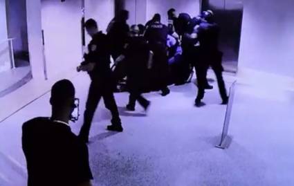 La turba policial rodea al sospechoso y lo golpea y se ve al transeunte que filma la escena