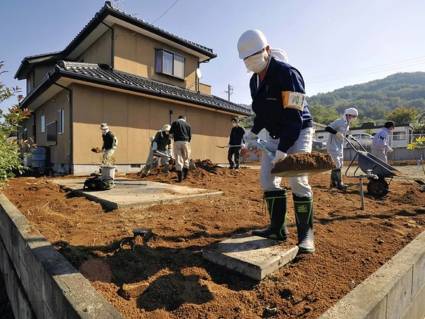 Voluntarios trabajan para descontaminar el suelo de un jardín de casa en la prefectura de Fukushima.