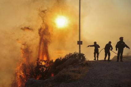 Bomberos intentan extinguir un incendio forestal que arde en Saronida, cerca de Atenas, Grecia