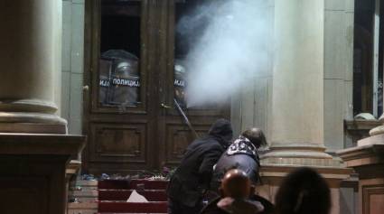 Manifestantes lanzan piedras a la policía que utiliza gases lacrimógenos en el Ayuntamiento de Belgrado, en Serbia